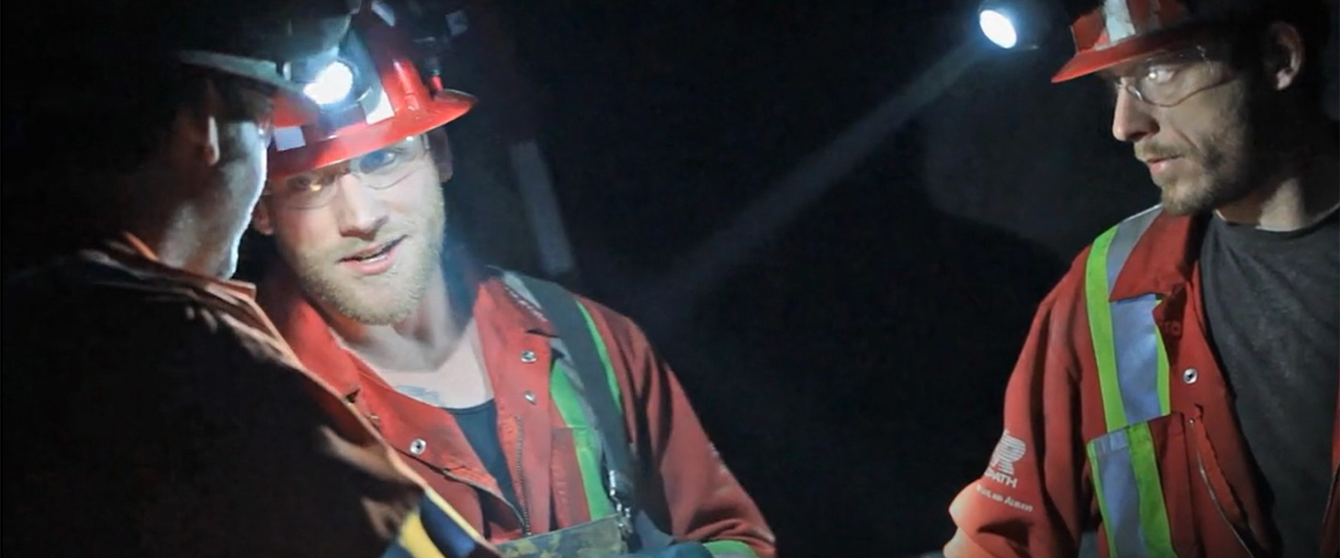 The website banner for the Accessibility page shows a group of Redpath miners having a conversation in the dark, dimly lit of the head lamps of their safety helmets.